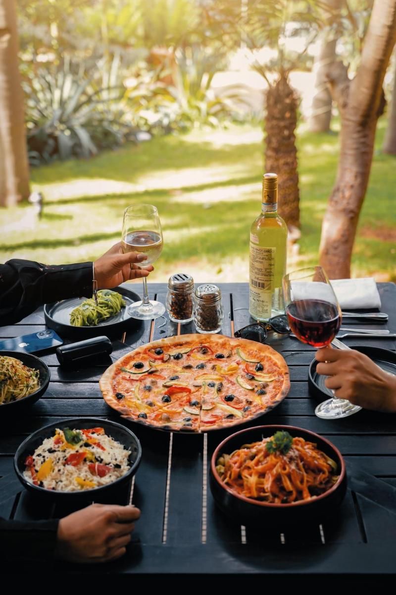 a table with two pizzas and plates of food and wine at Hyatt Hyderabad Gachibowli in Hyderabad