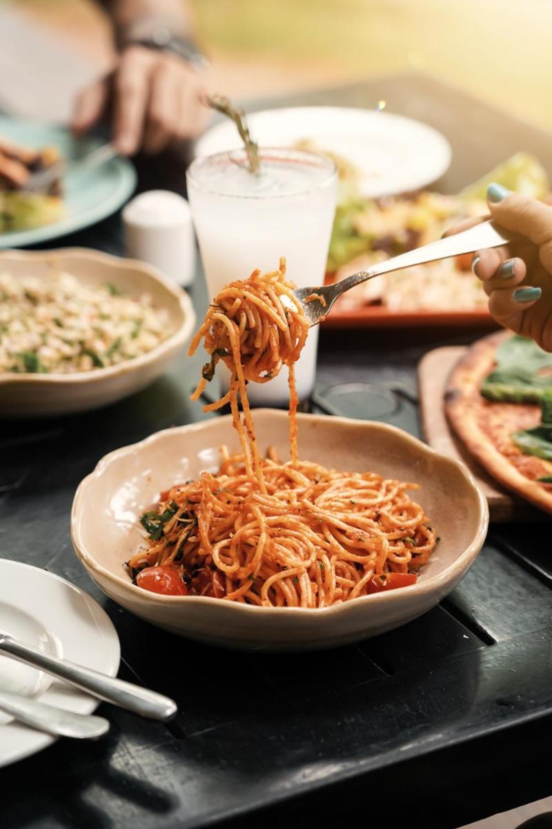 a bowl of spaghetti on a table with a fork at Hyatt Hyderabad Gachibowli in Hyderabad