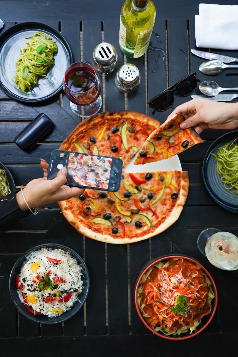 a group of people taking pictures of pizzas on a table at Hyatt Hyderabad Gachibowli in Hyderabad