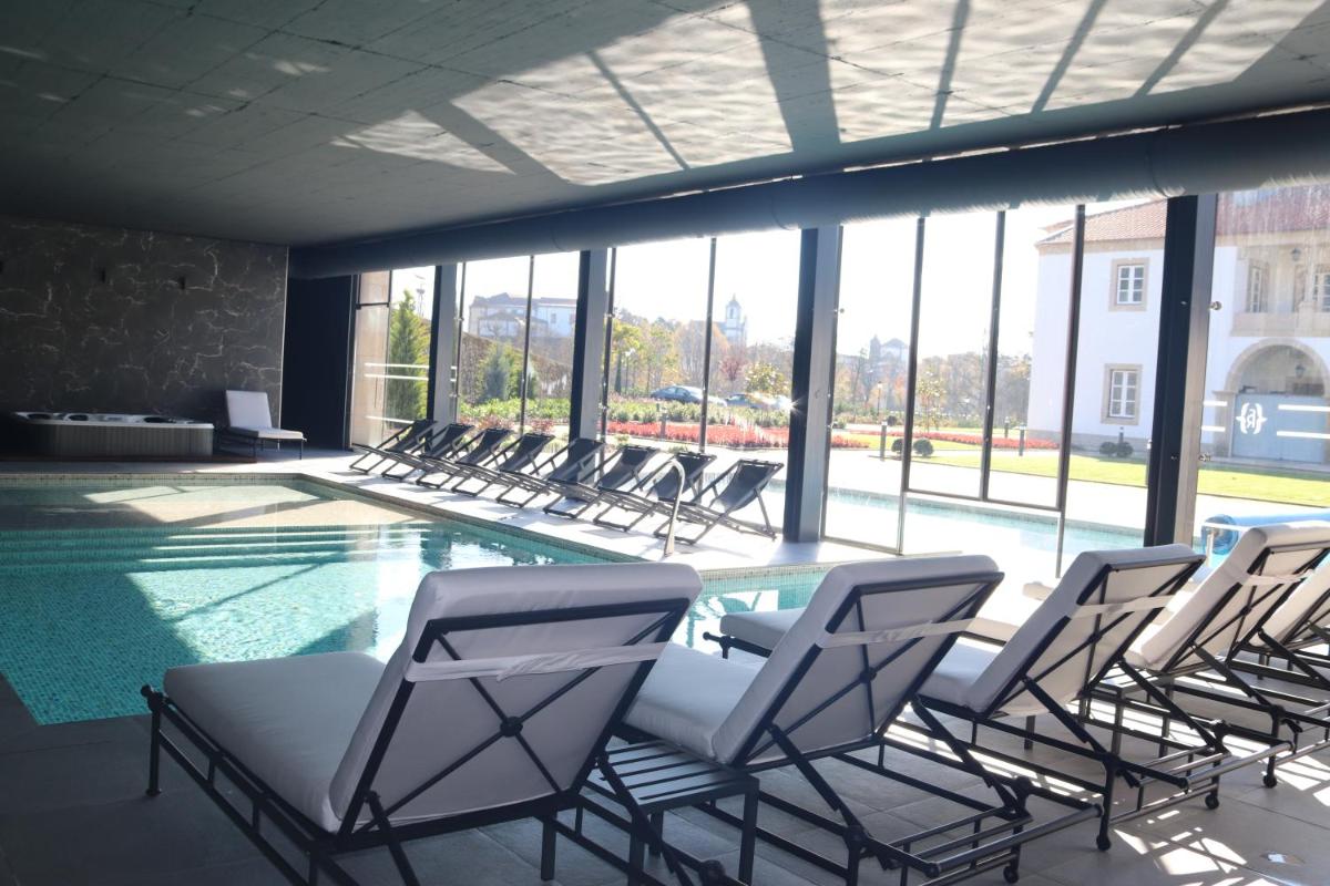 um grupo de cadeiras ao redor de uma piscina em Solar do Requeijo by Luna Hotels & Resorts em Arcos de Valdevez