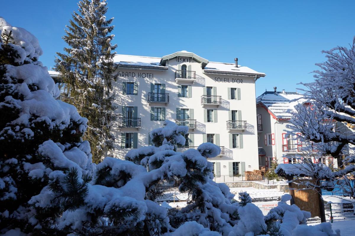 un bâtiment recouvert de neige devant un arbre dans l'établissement Grand Hotel Soleil d'Or, à Megève