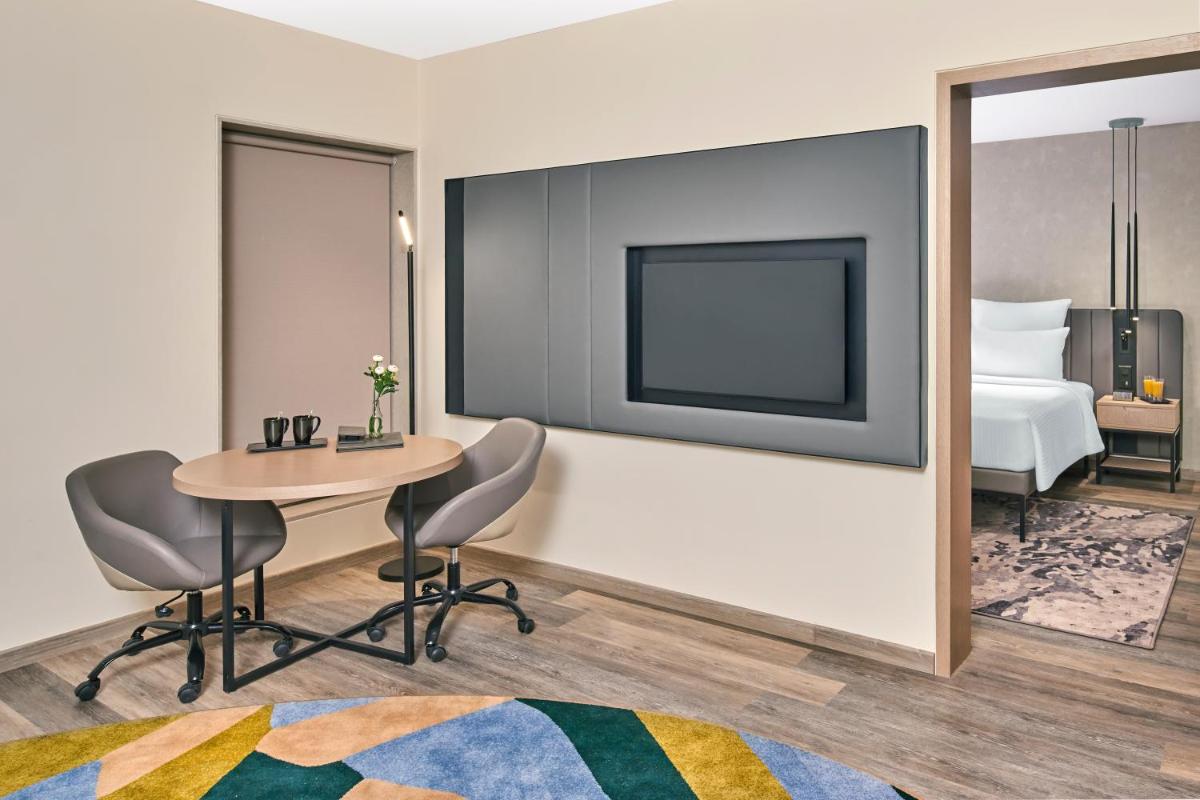 a hotel room with a table and chairs and a bed at Novotel Mumbai International Airport in Mumbai