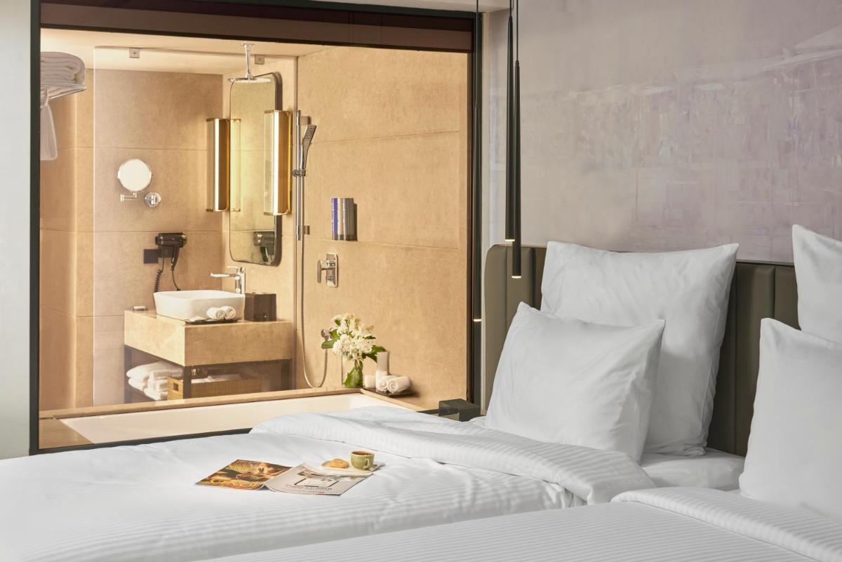 a bedroom with a large bed with a bathroom at Novotel Mumbai International Airport in Mumbai