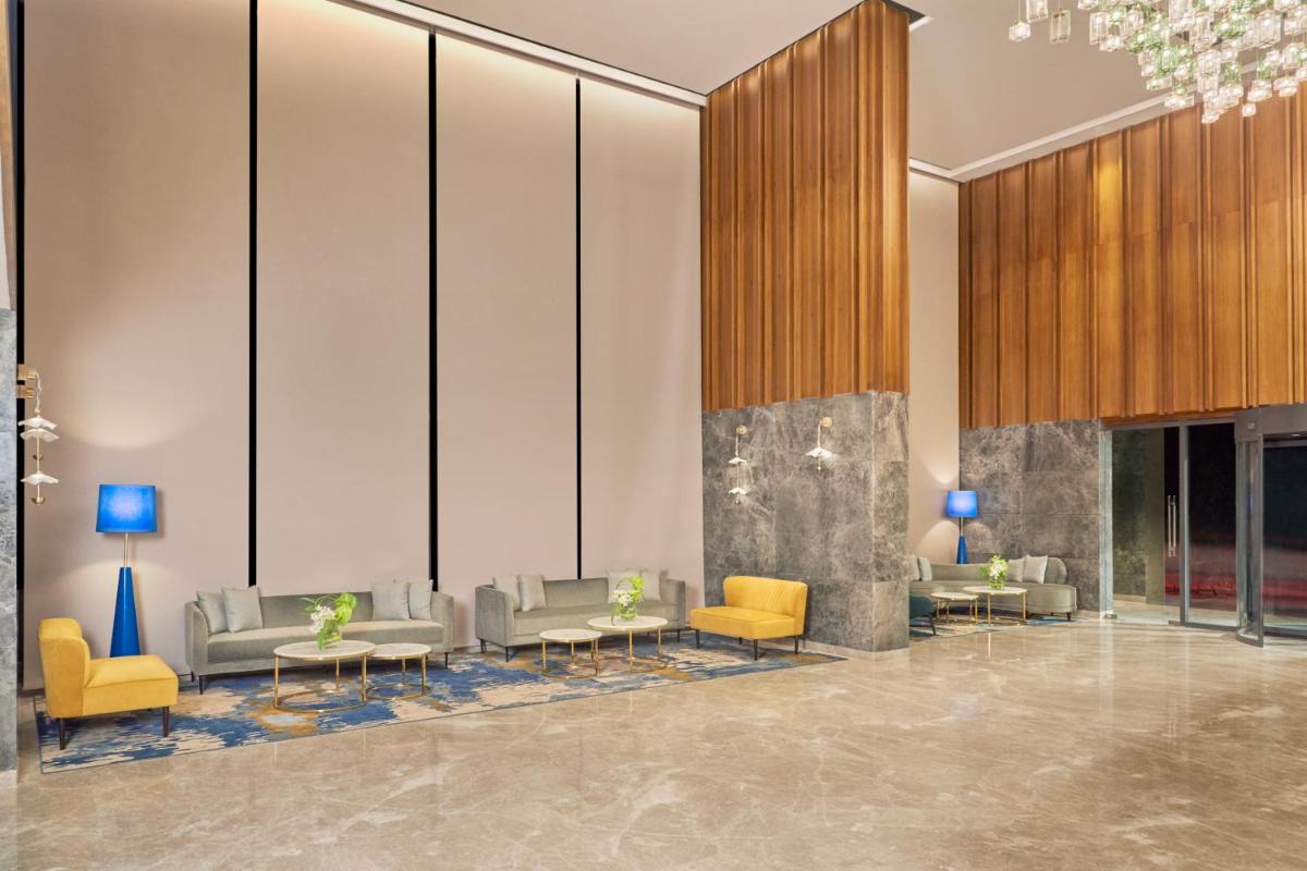 a lobby with couches and chairs and tables at Novotel Mumbai International Airport in Mumbai