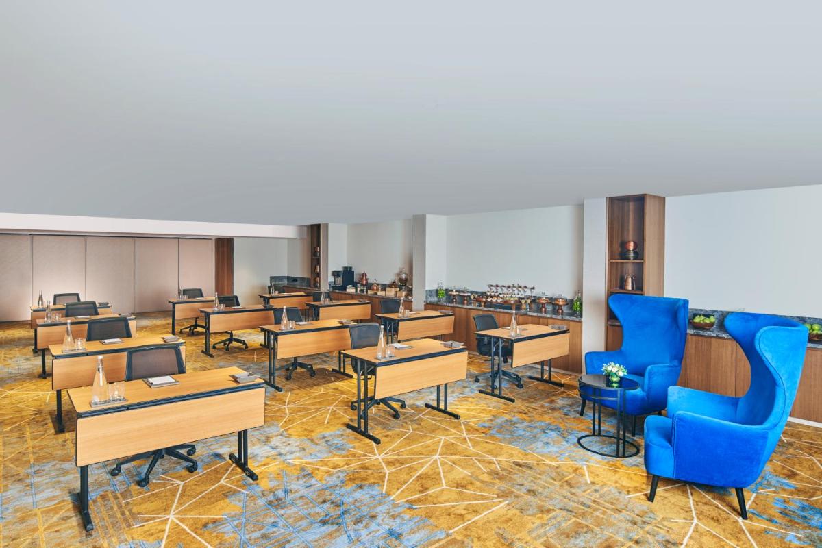 a classroom with tables and chairs and blue chairs at Novotel Mumbai International Airport in Mumbai