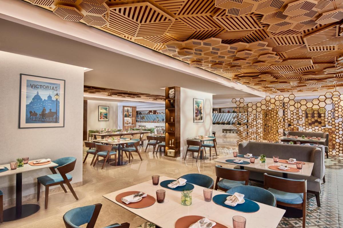 a restaurant with tables and chairs and a ceiling at Novotel Mumbai International Airport in Mumbai