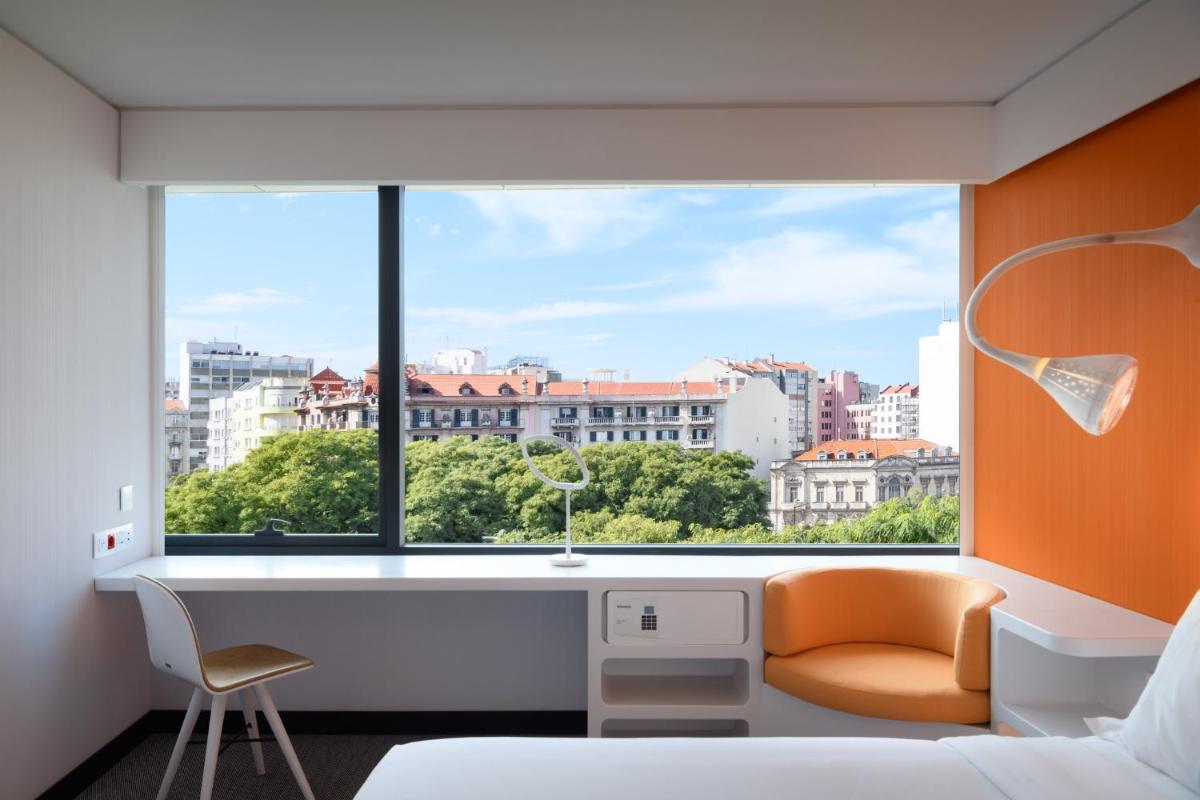 um quarto com uma janela com uma secretária e uma cadeira em EVOLUTION Lisboa Hotel em Lisboa