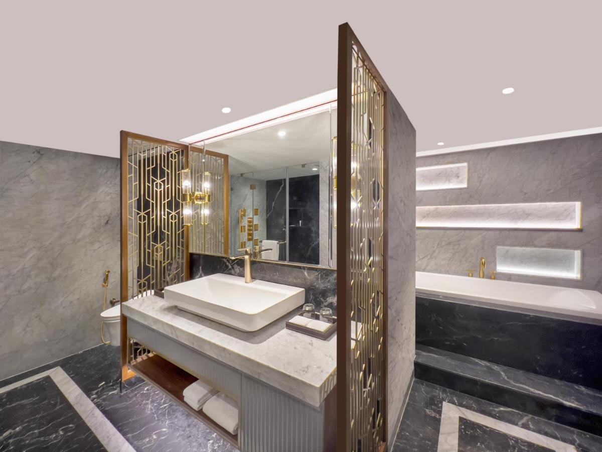a bathroom with a sink and a mirror and a tub at Radisson Blu Hotel & Suites GRT Chennai in Chennai