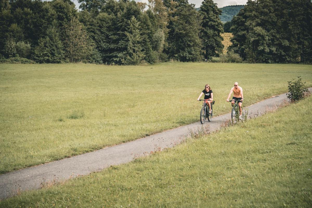 zwei Personen fahren mit dem Fahrrad auf einer unbefestigten Straße durch ein Feld in der Unterkunft Neumühle Resort & Spa in Hammelburg + 37 Fotos