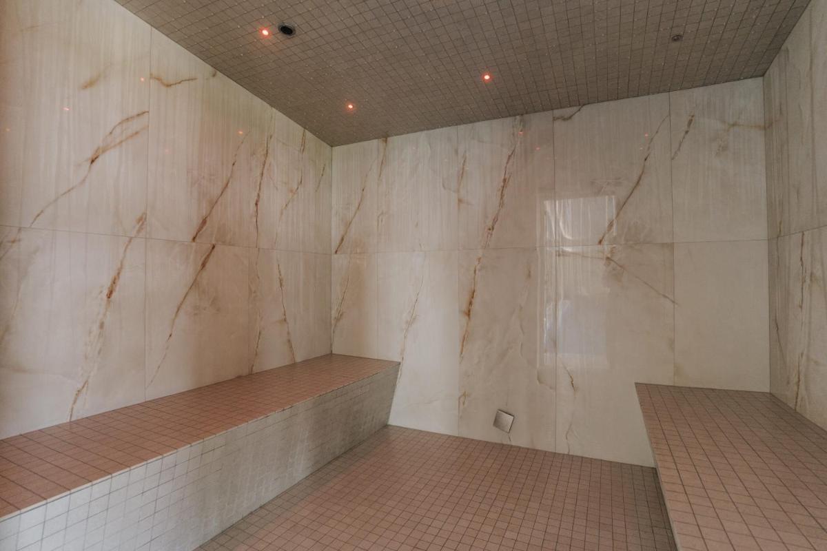 uma casa de banho com paredes em mármore branco e piso em azulejo em Conimbriga Hotel do Paço em Condeixa a Nova
