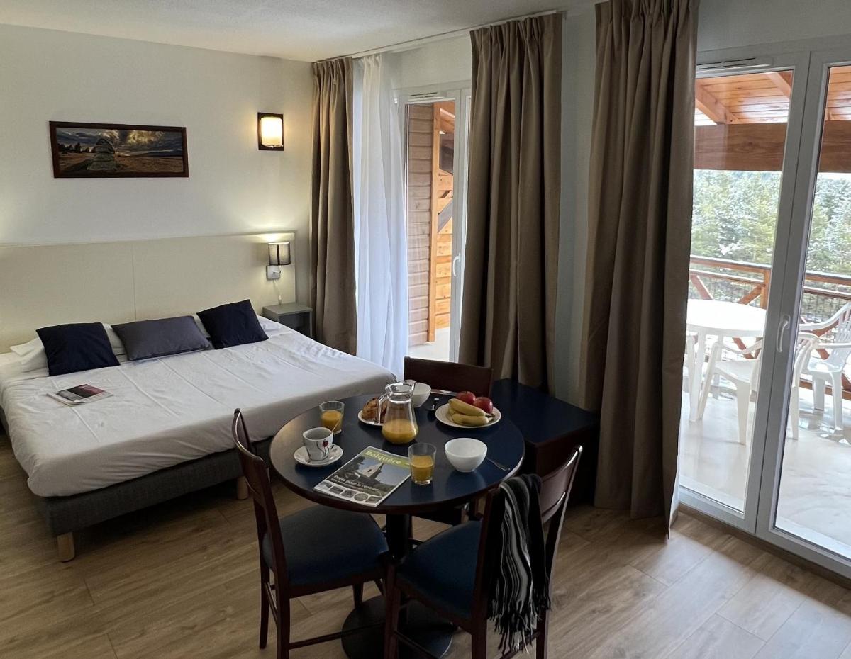 une chambre d'hôtel avec un lit, une table et des chaises dans l'établissement Vacancéole - Appart'Vacances Pyrénées 2000, à Bolquère-Pyrénées 2000