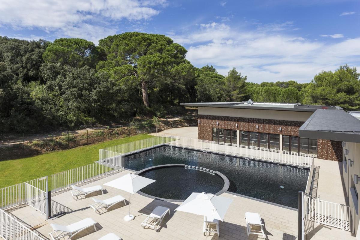 - une vue sur une piscine avec des chaises et un bâtiment dans l'établissement Residhotel Résidence Pont du Gard, à Remoulins
