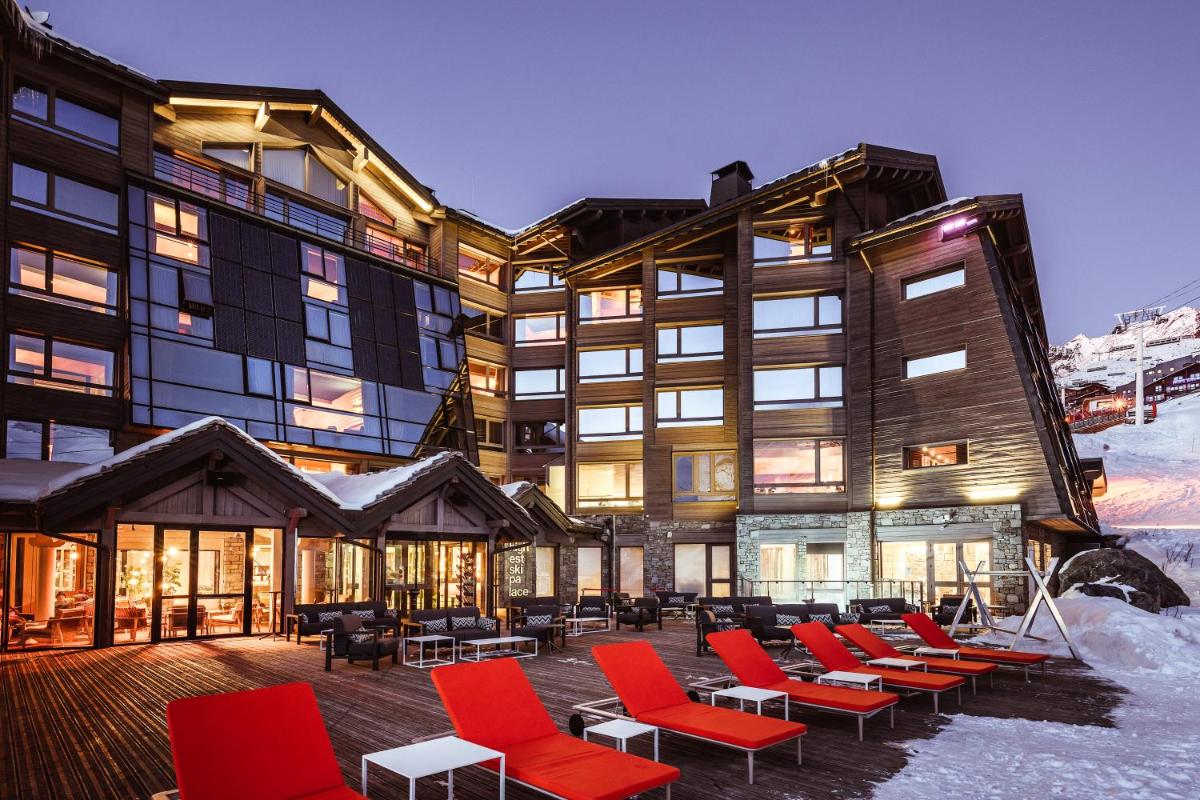 - un grand bâtiment avec des chaises rouges en face dans l'établissement Altapura Hôtel & Spa Val Thorens, à Val Thorens