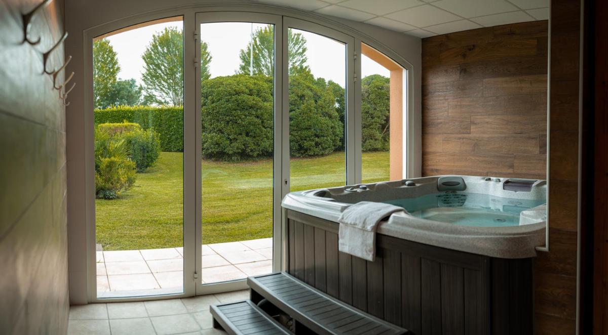 La salle de bains est pourvue d'une baignoire et d'une grande fenêtre. dans l'établissement Alysson Hôtel, à Oloron-Sainte-Marie