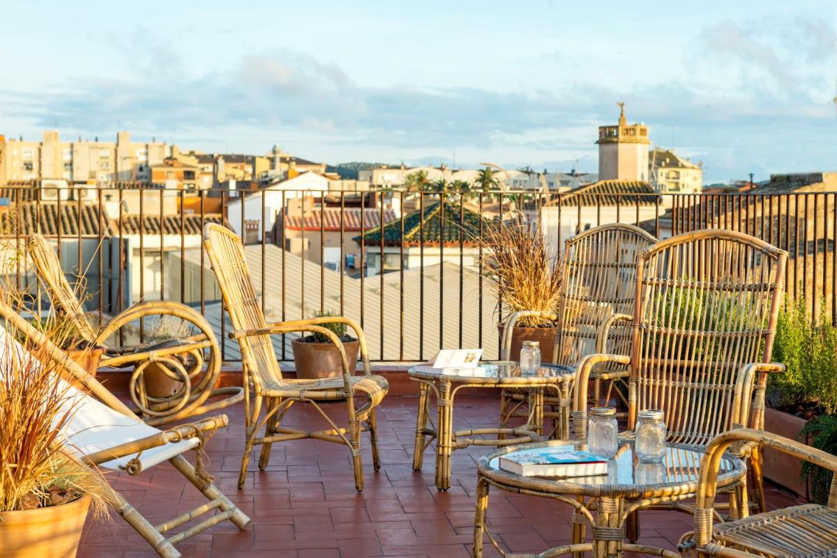 Un patio con sillas y mesas en un balcón. en Can Mascort Eco Hotel, en Palafrugell