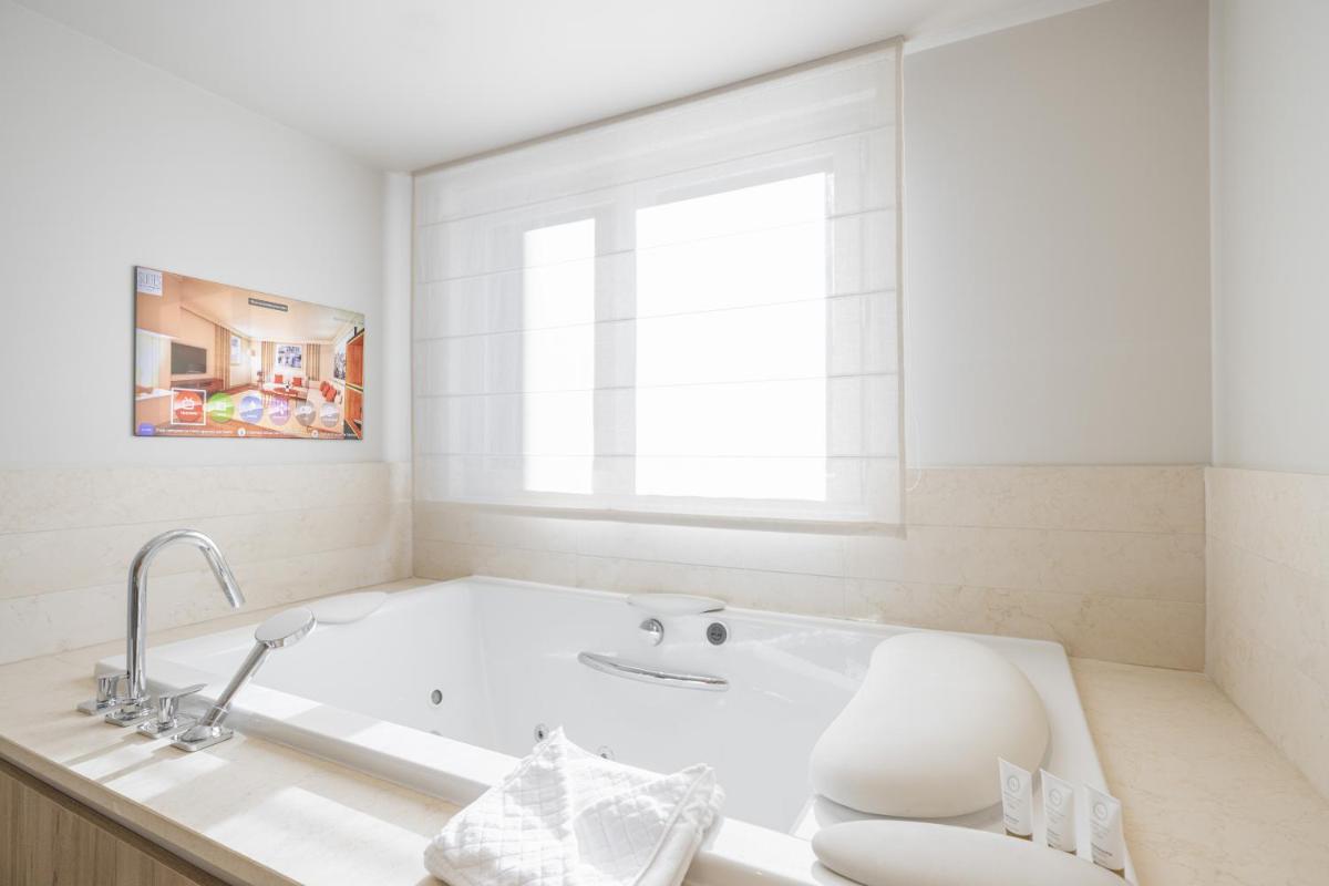 La salle de bains blanche est pourvue d'une baignoire et d'une fenêtre. dans l'établissement Les Suites de la Potinière, à Courchevel La salle de bains blanche est pourvue d'une baignoire et d'une fenêtre. dans l'établissement Les Suites de la Potinière, à Courchevel