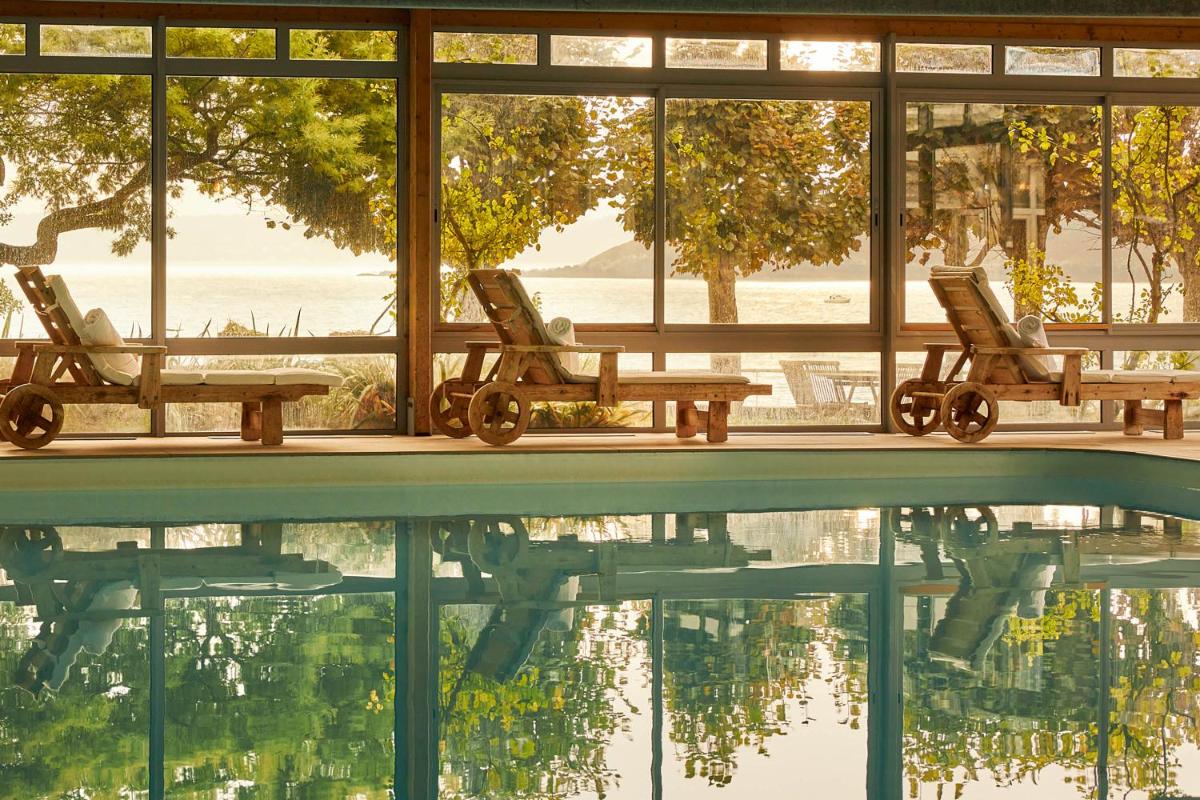 une piscine avec deux chaises et une table et de l'eau dans l'établissement Le Grand Hotel des Bains & Spa - Bretagne, à Locquirec