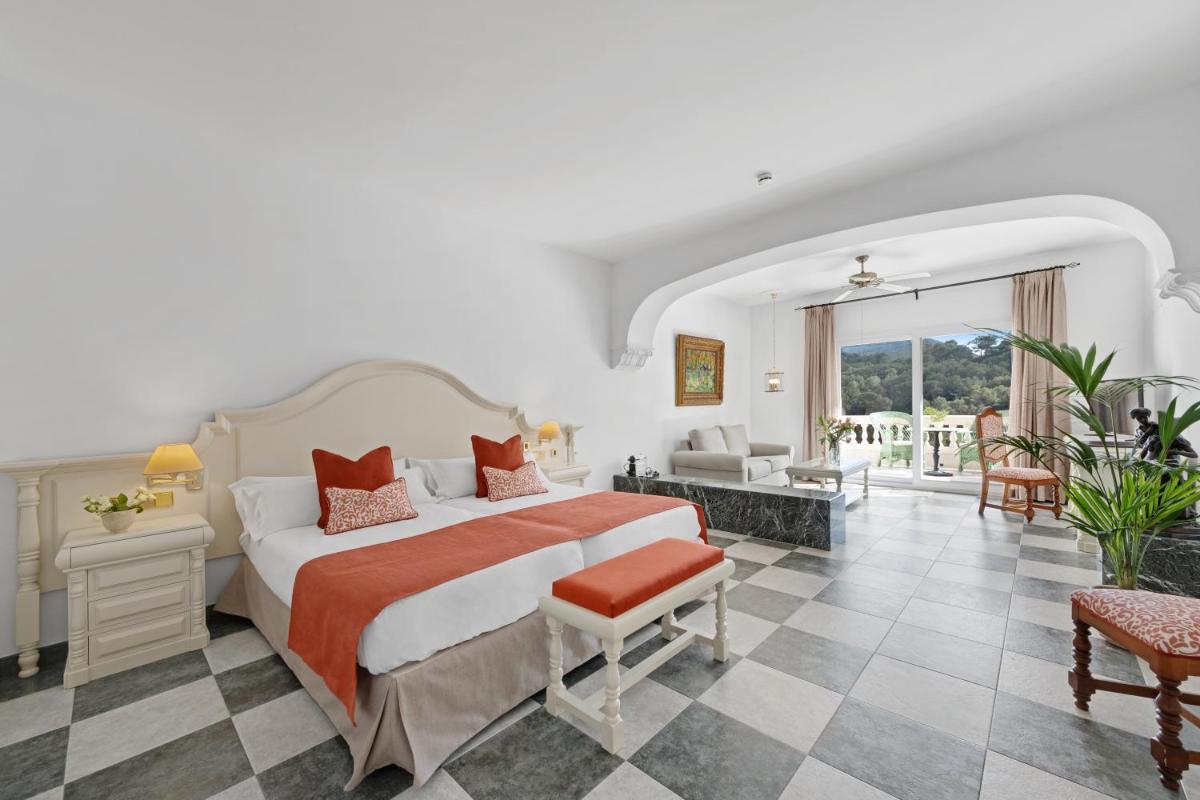 Un dormitorio con una cama y una sala de estar. en La Moraleja The Quiet Hotel - Adults Only, en Cala de Sant Vicent