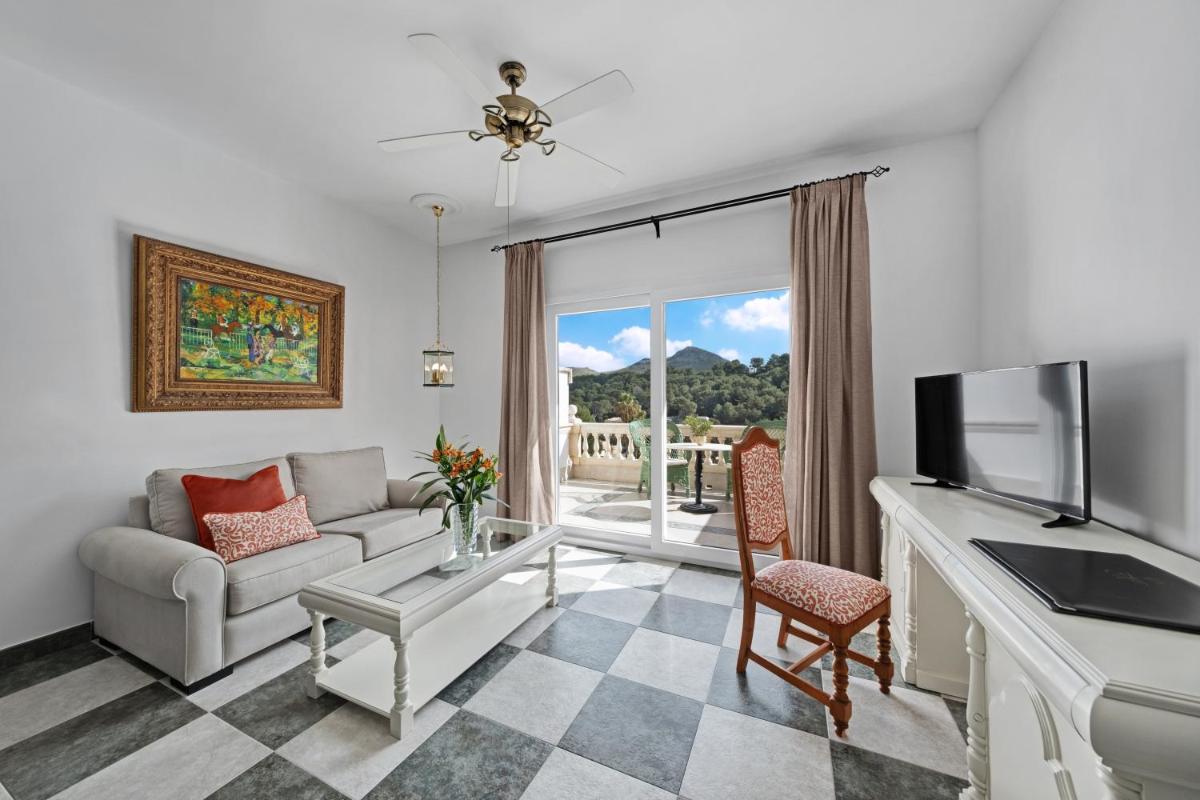 Una sala de estar con un sofá y un televisor. en La Moraleja The Quiet Hotel - Adults Only, en Cala de Sant Vicent