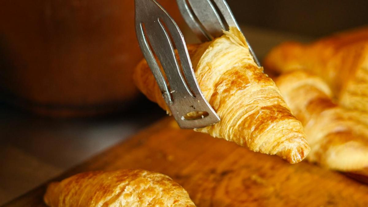 a person cutting a loaf of bread with a knife at InterContinental Marine Drive Mumbai by IHG in Mumbai