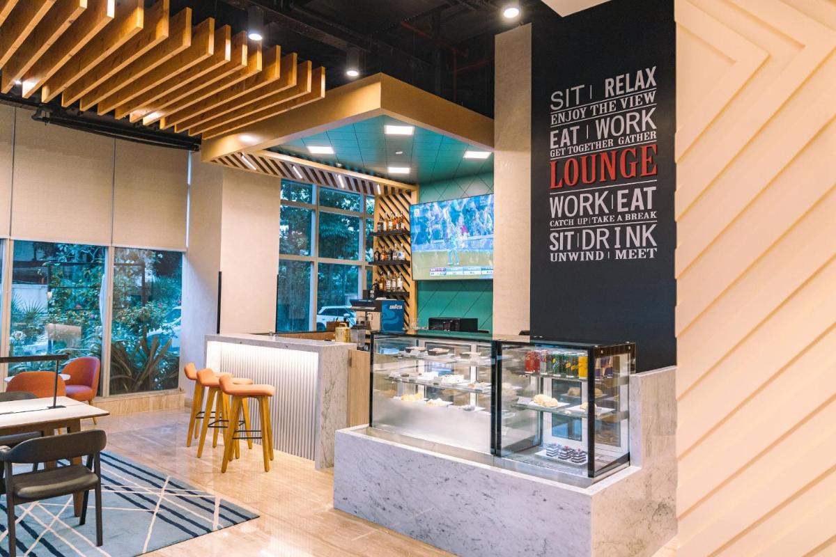 a restaurant with a counter with chairs and tables at Holiday Inn Bengaluru Racecourse by IHG in Bengaluru a restaurant with a counter with chairs and tables at Holiday Inn Bengaluru Racecourse by IHG in Bengaluru