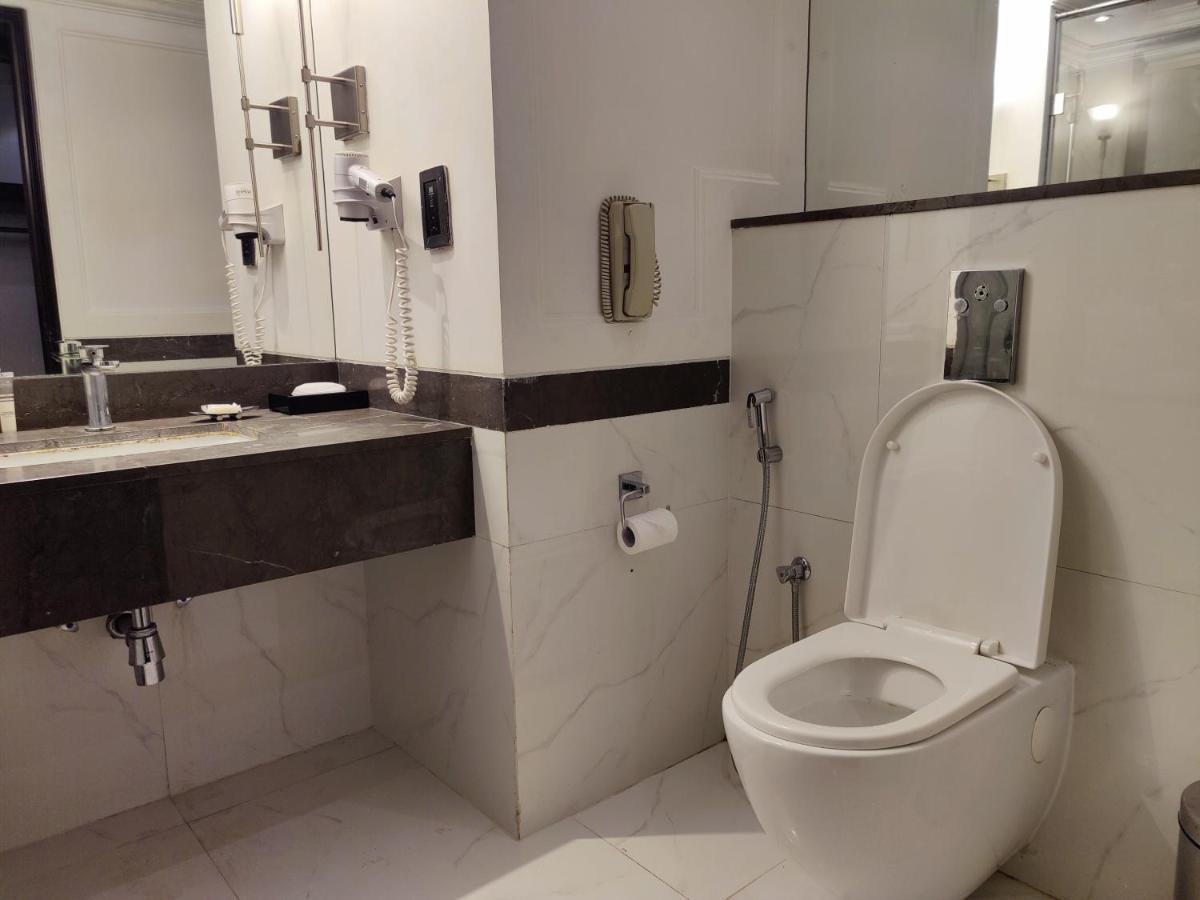 a bathroom with a toilet and a phone on the wall at Hotel Royal Orchid Bangalore in Bengaluru