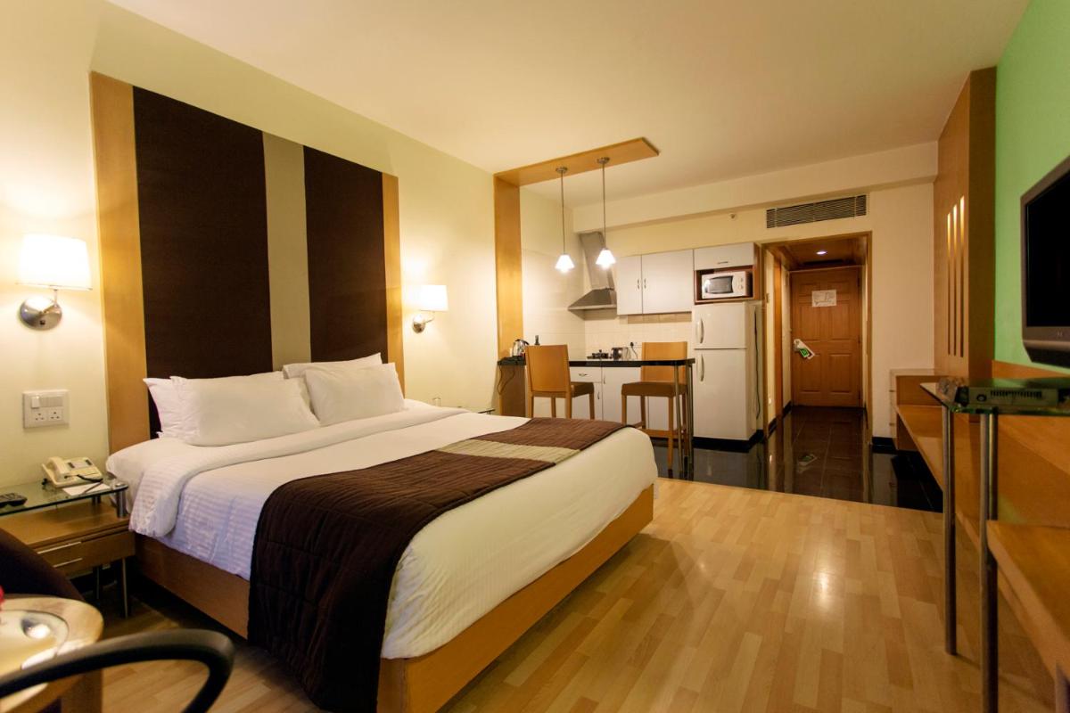 a hotel room with a large bed and a kitchen at Hotel Royal Orchid Bangalore in Bengaluru