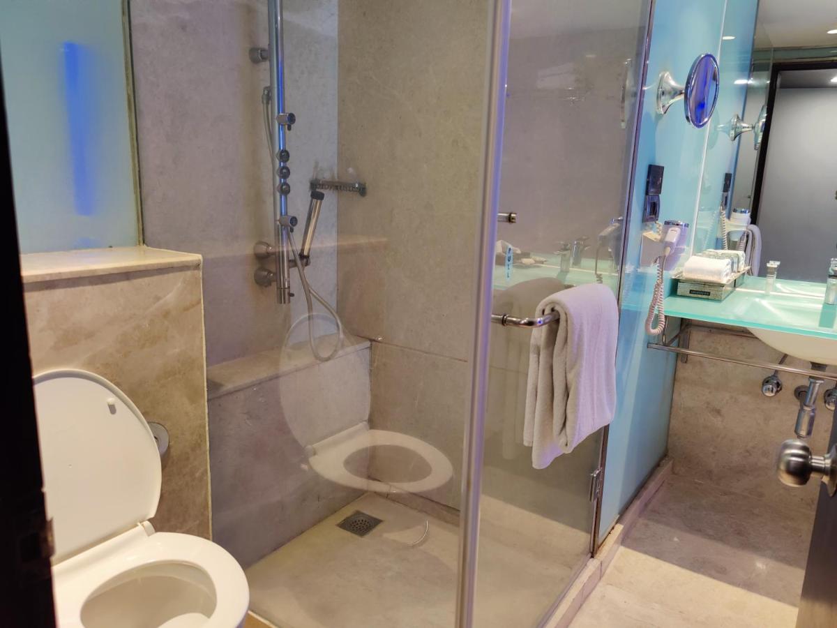 a bathroom with a shower and a toilet and a sink at Hotel Royal Orchid Bangalore in Bengaluru
