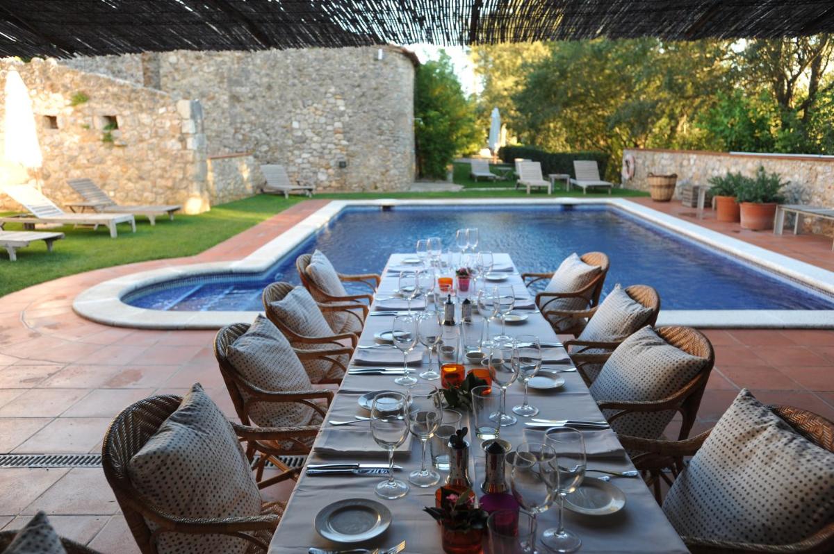 una mesa larga con copas de vino frente a una piscina en Mas Falgarona Hotel Boutique & SPA, en Avinyonet de Puigventós una mesa larga con copas de vino frente a una piscina en Mas Falgarona Hotel Boutique & SPA, en Avinyonet de Puigventós