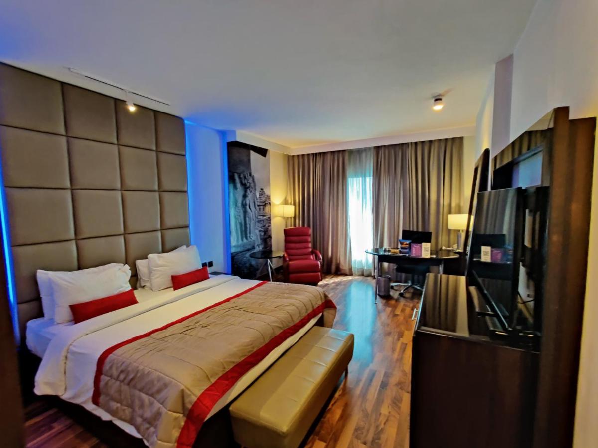 a hotel room with a large bed and a television at Hotel Royal Orchid Bangalore in Bengaluru