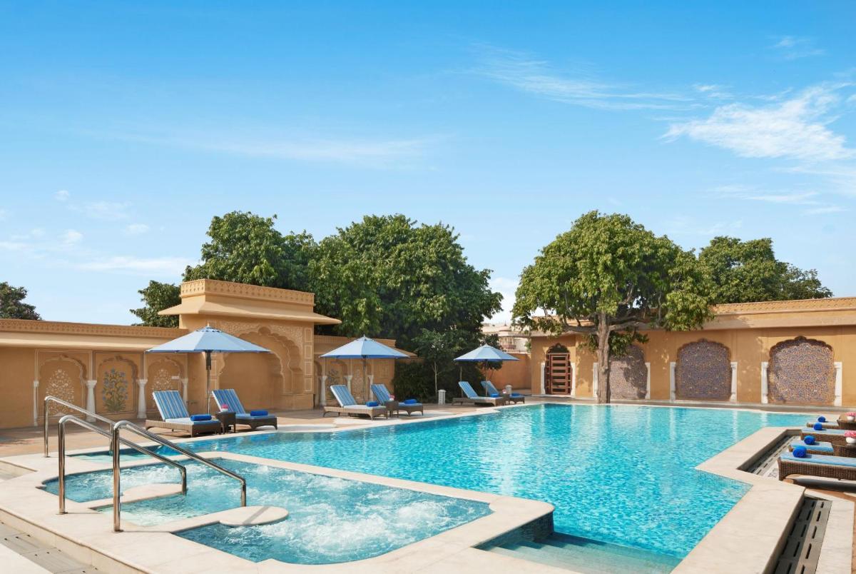 a pool at a resort with chairs and umbrellas at Sawai Man Mahal in Jaipur
