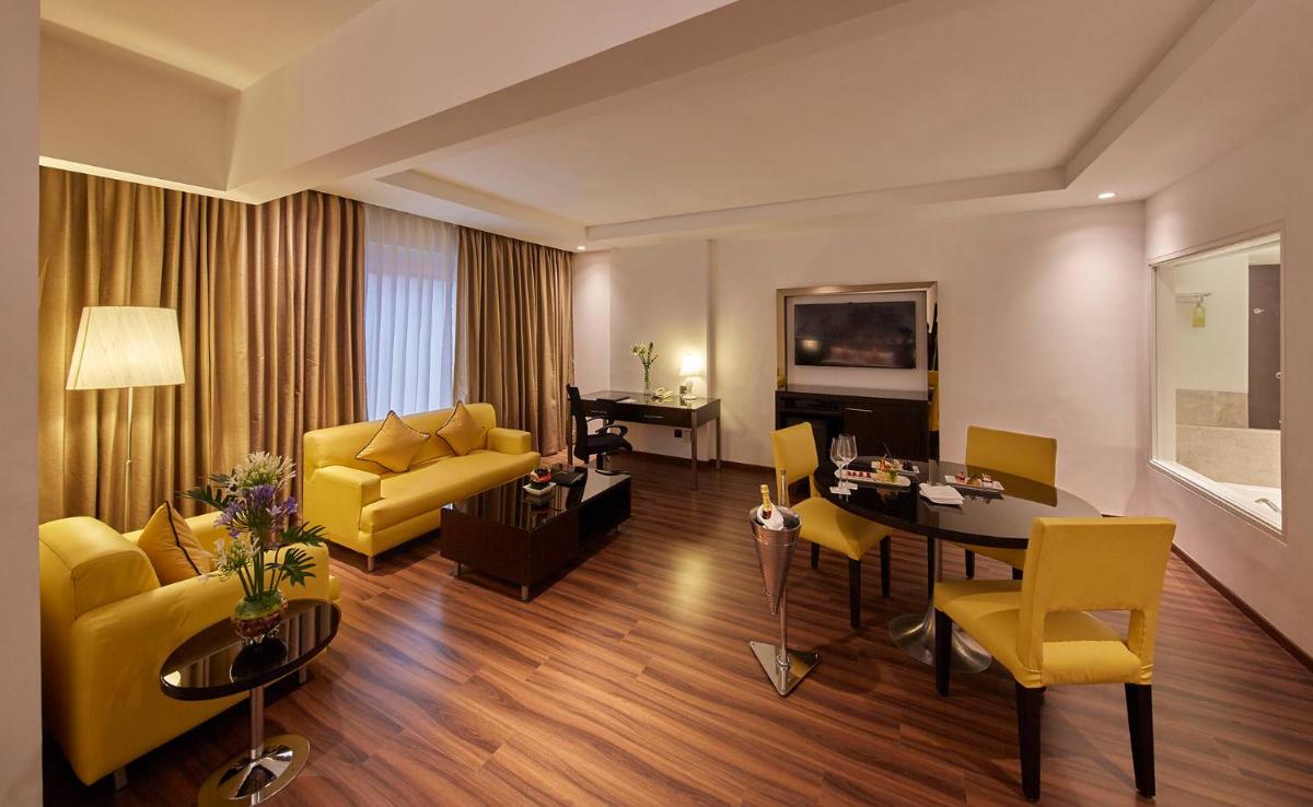 a living room with a yellow couch and a table at Hotel Royal Orchid Bangalore in Bengaluru
