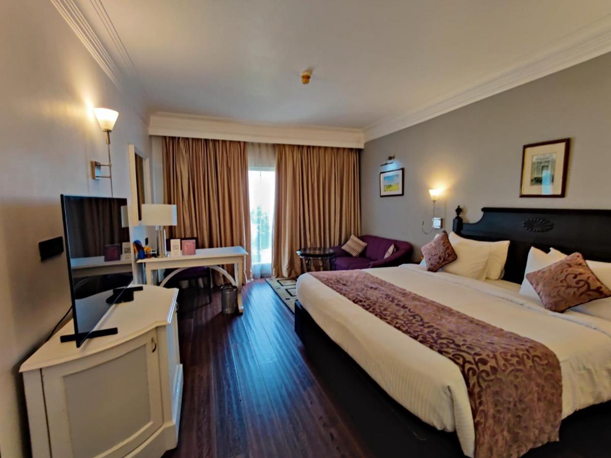 a hotel room with a bed and a flat screen tv at Hotel Royal Orchid Bangalore in Bengaluru