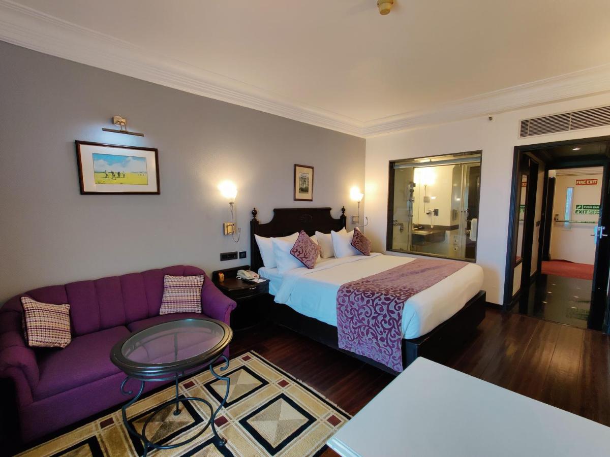 a hotel room with a bed and a purple couch at Hotel Royal Orchid Bangalore in Bengaluru