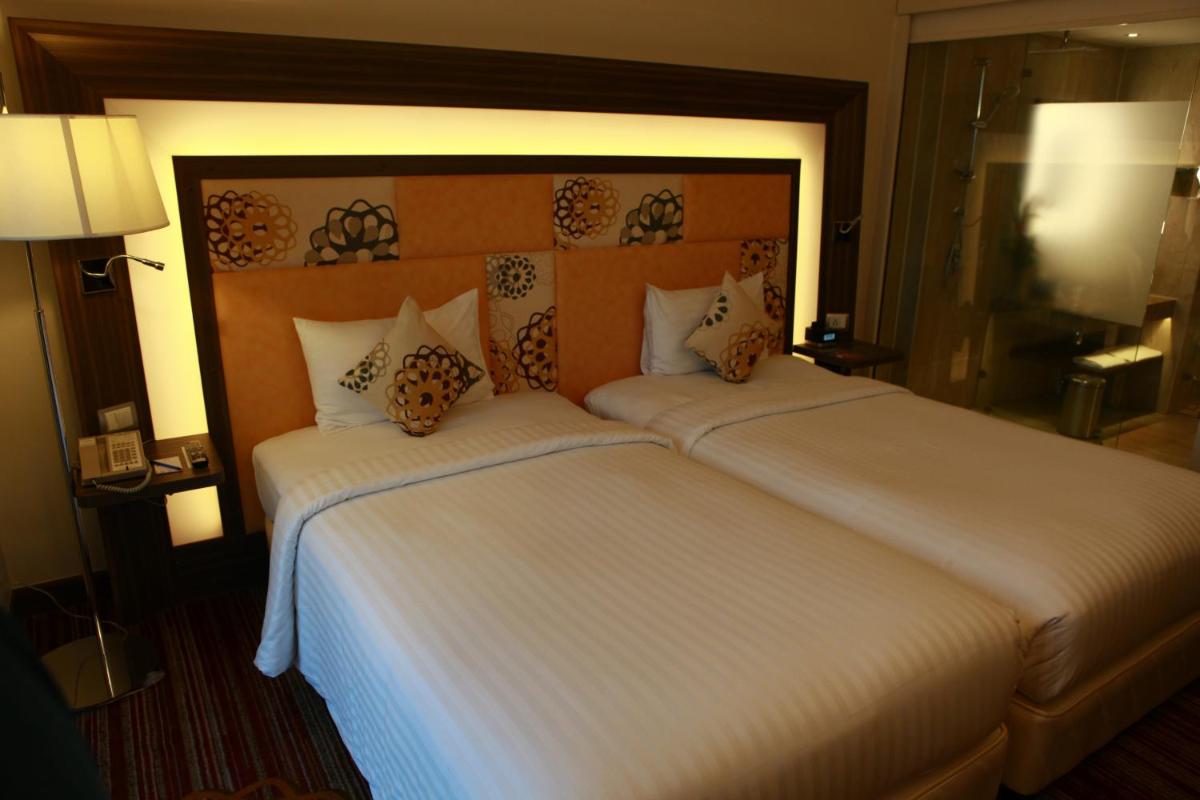 a hotel room with a large bed with white sheets at Novotel Pune Viman Nagar Road in Pune