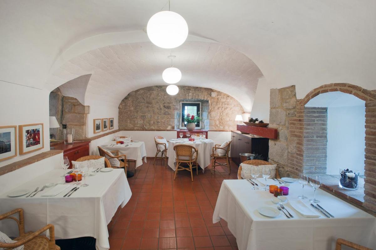 un restaurante con mesas y sillas blancas en una habitación en Mas Falgarona Hotel Boutique & SPA, en Avinyonet de Puigventós