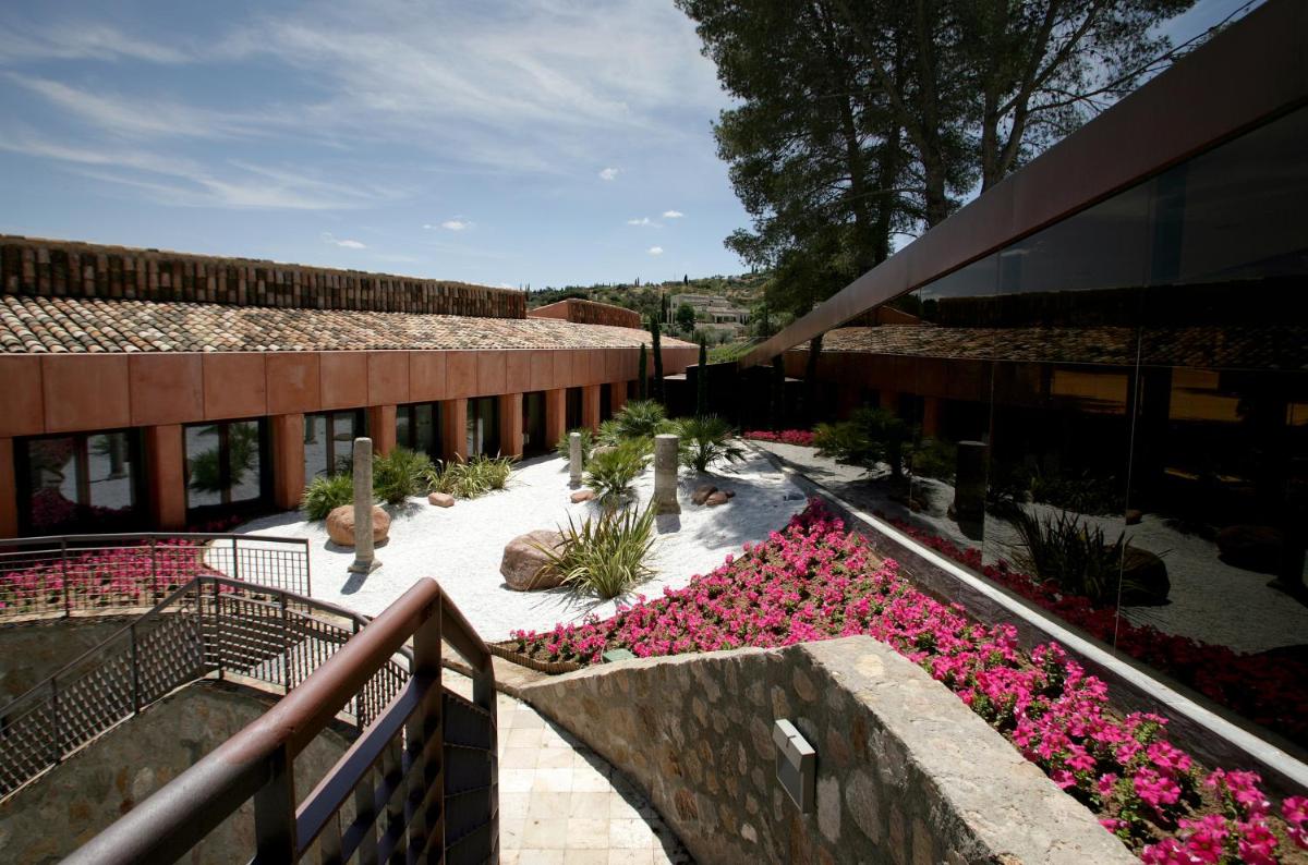 Un edificio con un jardín de flores rosas en un patio. en Hotel Cigarral el Bosque, en Toledo