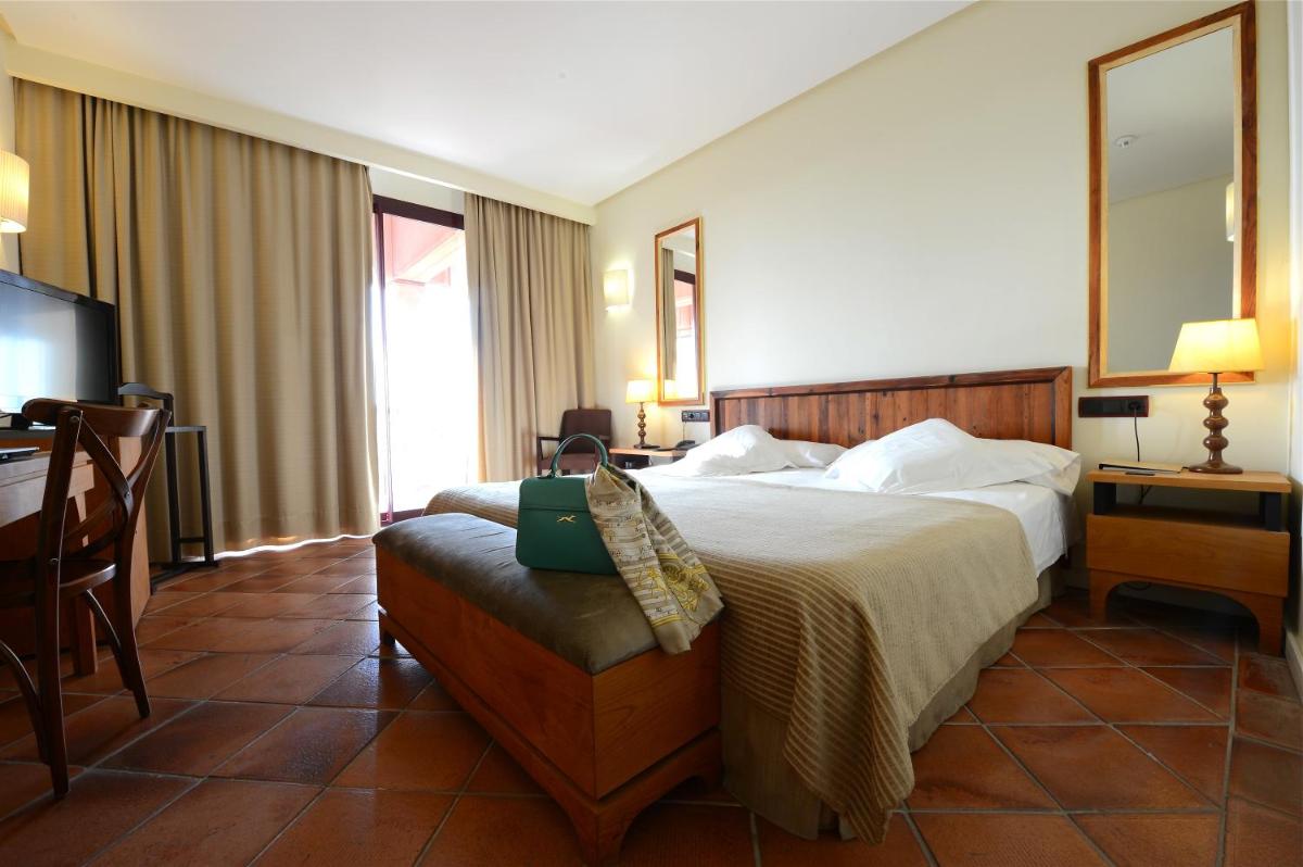 Una habitación de hotel con una cama, una silla y un espejo. en Hotel Cigarral el Bosque, en Toledo