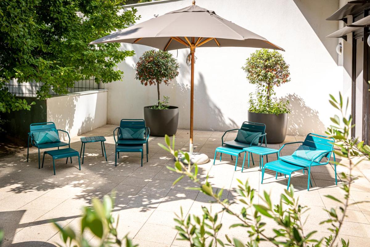 un groupe de chaises et un parasol sur une terrasse dans l'établissement Fraser Suites Paris La Défense, à Courbevoie