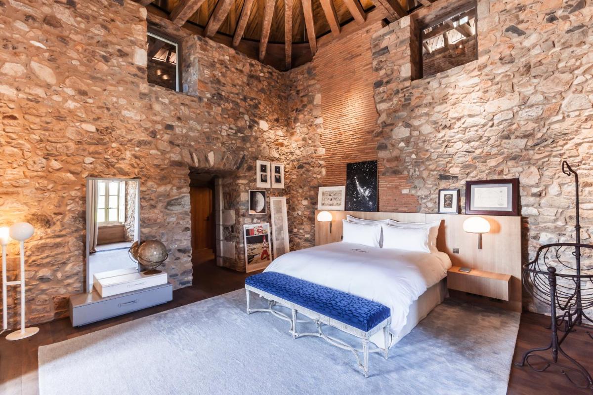 une chambre avec un lit et un mur en pierre dans l'établissement Domaine des Etangs, Auberge Collection, à Massignac
