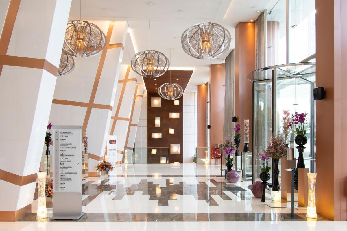 um lobby com vários lustres e flores no chão em EPIC SANA Lisboa Hotel em Lisboa