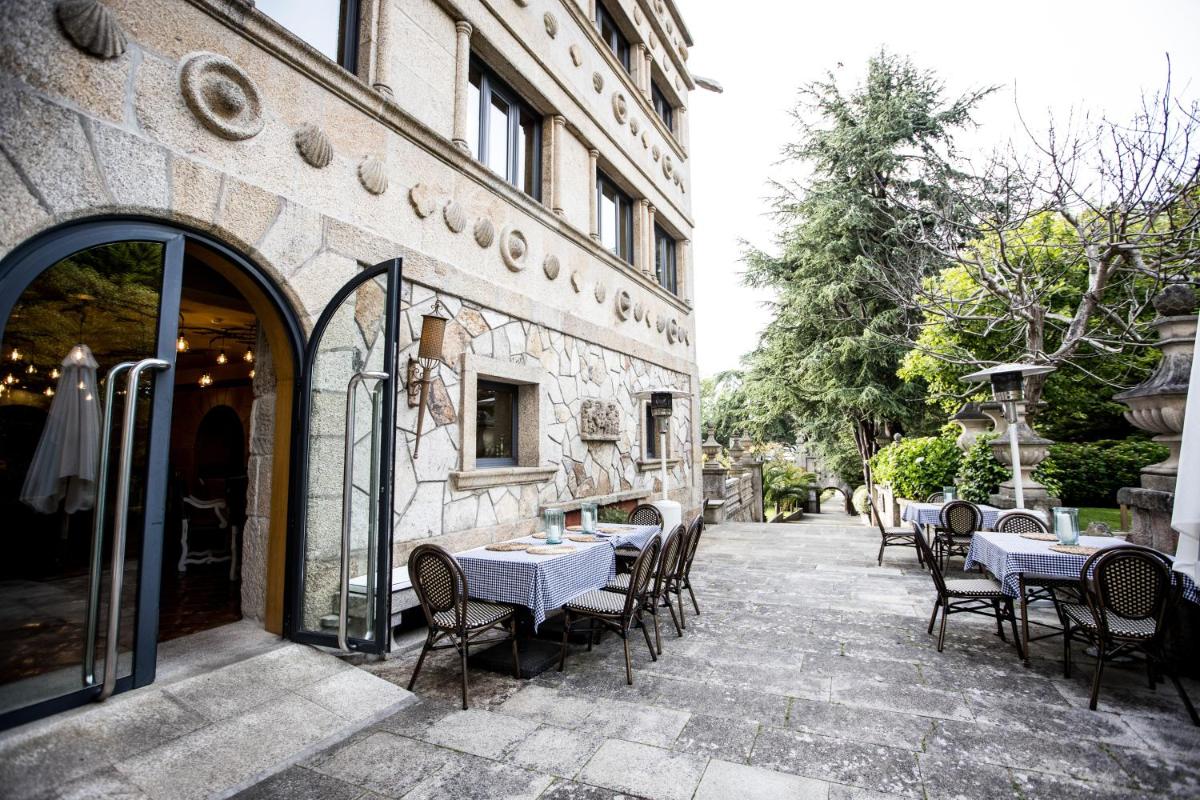 Un patio con mesas y sillas afuera de un edificio. en Pazo Los Escudos Hotel Spa & Resort, en Vigo