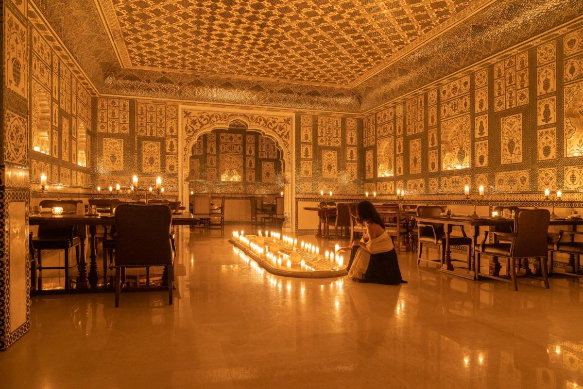 a woman sitting in the middle of a room with a large ceiling at The Leela Palace Jaipur in Jaipur
