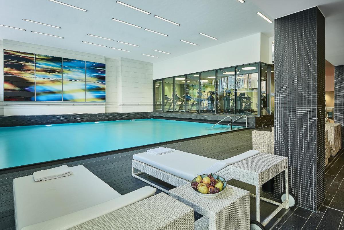 ein Swimmingpool mit zwei Stühlen und einem Tisch in der Unterkunft Pullman Berlin Schweizerhof in Berlin