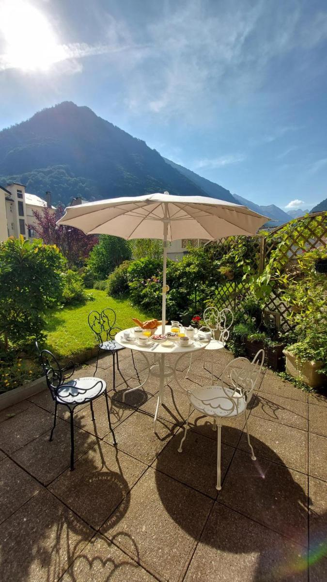 une table et deux chaises avec un parasol dans l'établissement Hôtel-Résidence Le Lys, à Cauterets