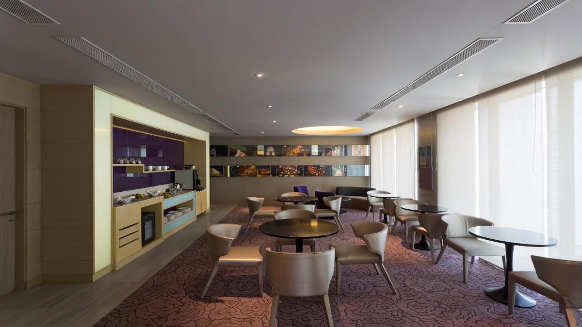 a dining room with tables and chairs and a tv at Holiday Inn New Delhi Aerocity by IHG in New Delhi