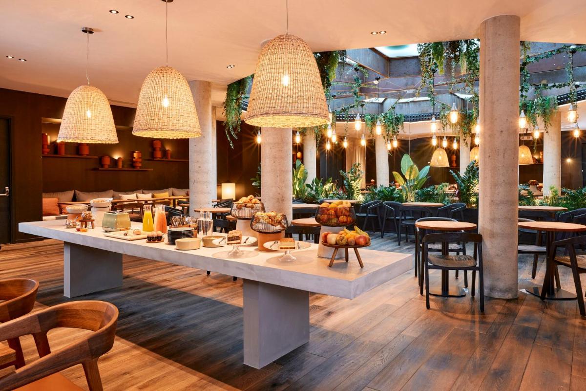 un restaurant avec une grande table au milieu d'une pièce dans l'établissement Le Bellune Paris, à Paris