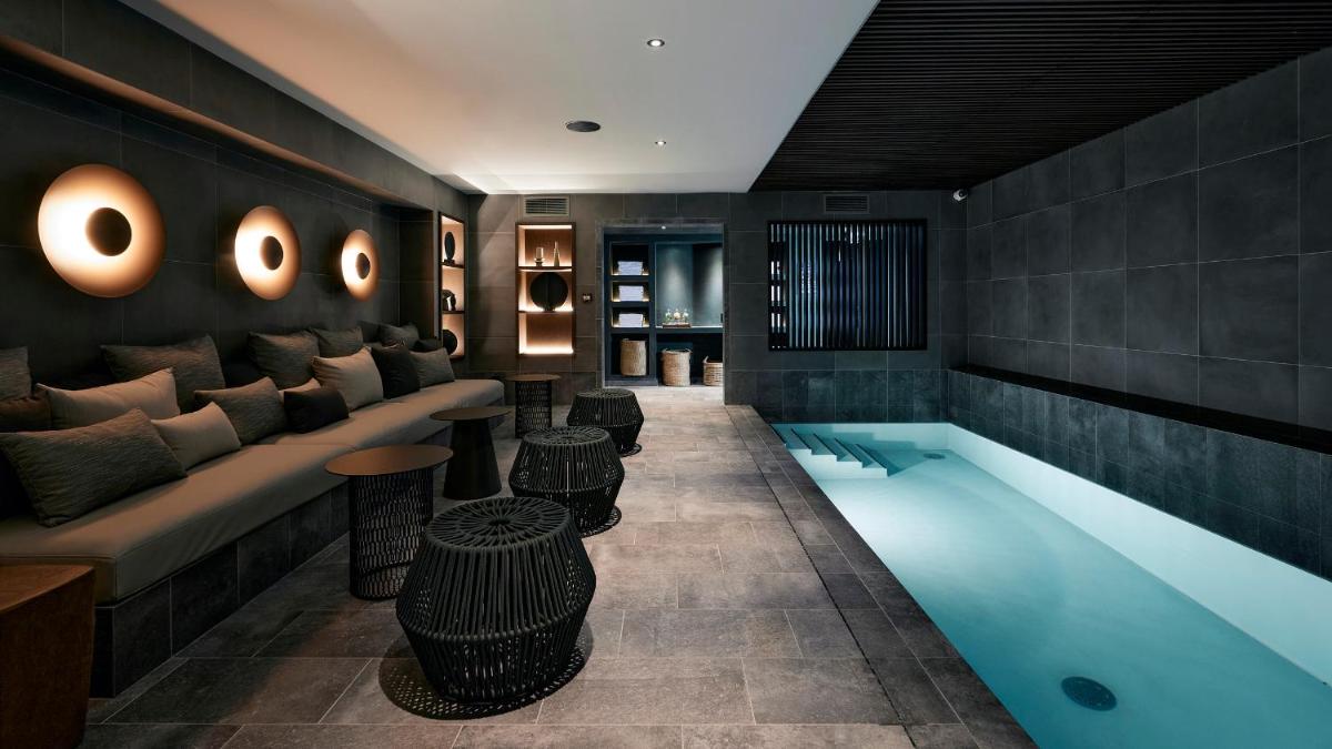 - un hall avec une piscine, un canapé et des tables dans l'établissement Le Bellune Paris, à Paris