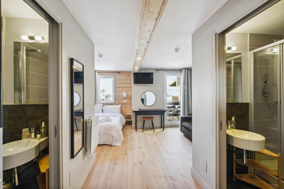 une salle de bain avec deux lavabos et un lit dans une chambre dans l'établissement Hotel Turan & Spa, à Les Deux Alpes