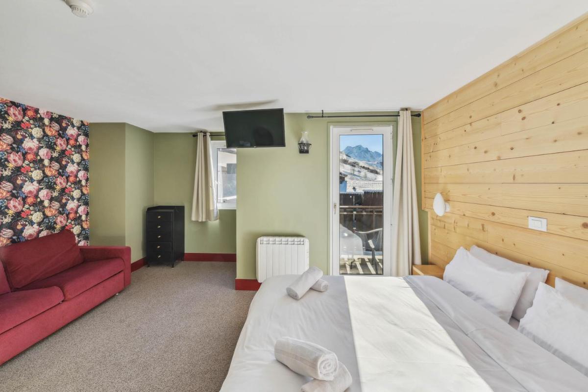 une chambre avec un grand lit et un canapé rouge dans l'établissement Hotel Turan & Spa, à Les Deux Alpes